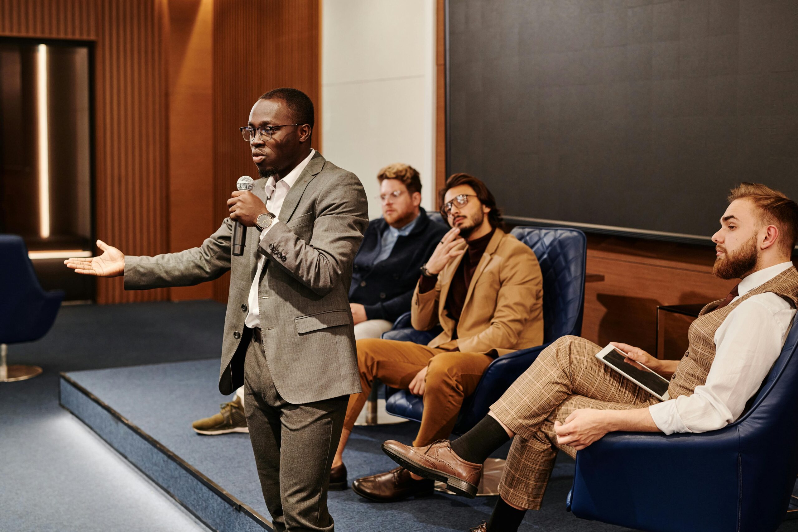 A business professional presenting at a conference with a diverse and attentive audience.